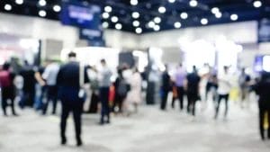 Blurred exhibition event in hall with many people on background. many businessmen are walking in the seminar